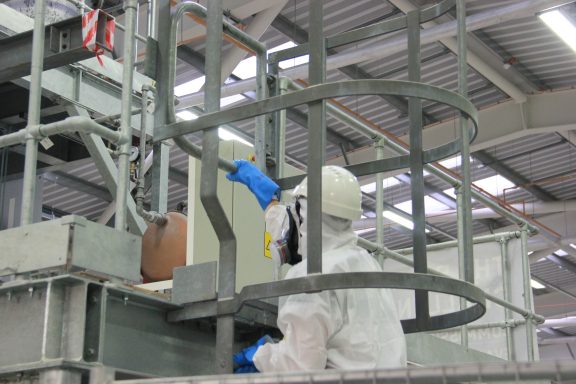 A person wearing a white safety suit climbs the ladder of the Big Rig facility