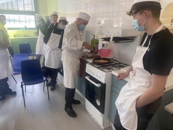 A man demonstrates how to cook to a group of students