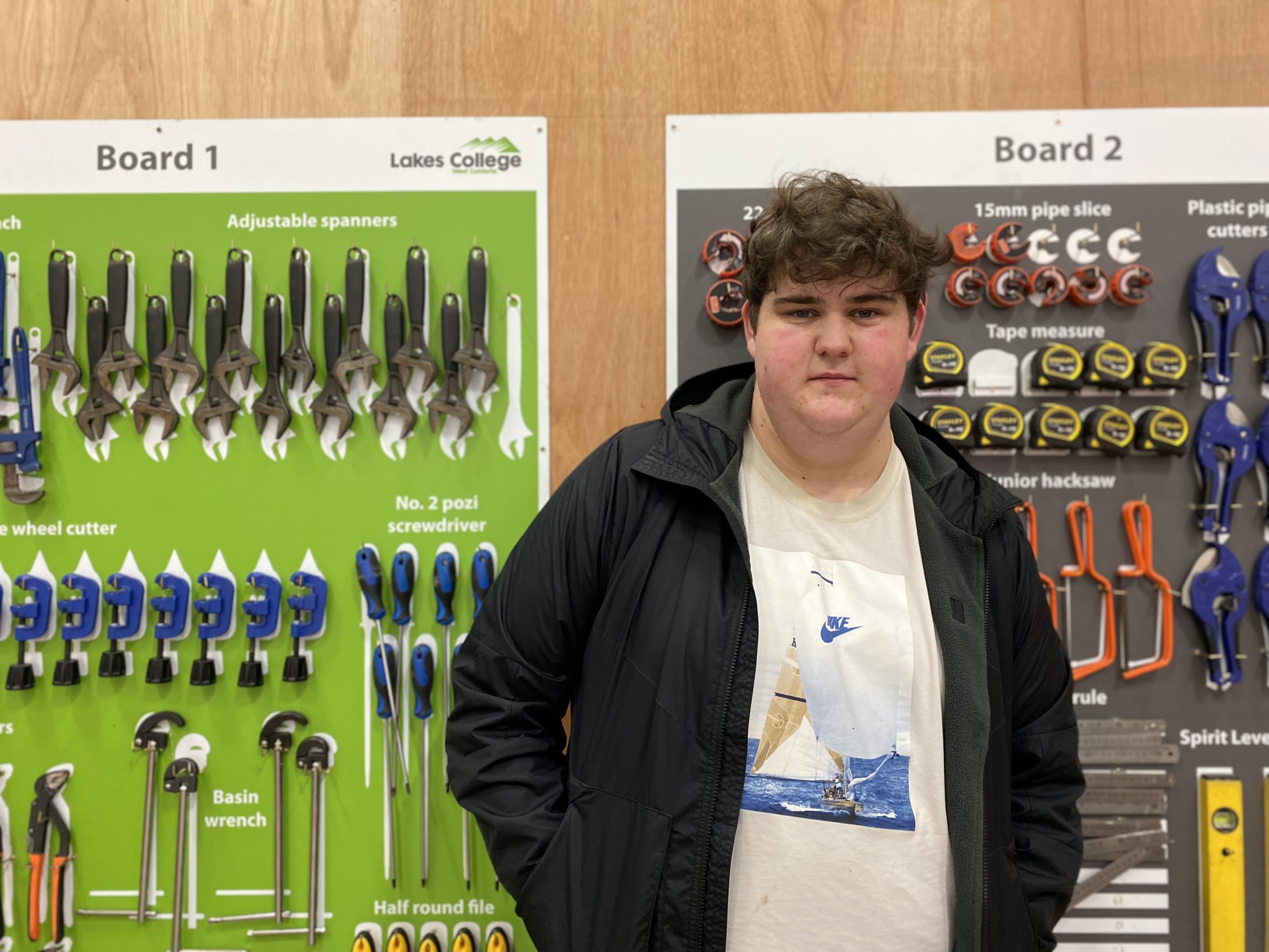 A man stands in front of plumbing tools on a rack