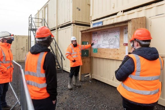 A group of workers are briefed on a construction site