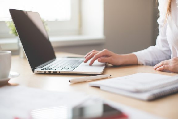 A woman sits at a desk using a laptop