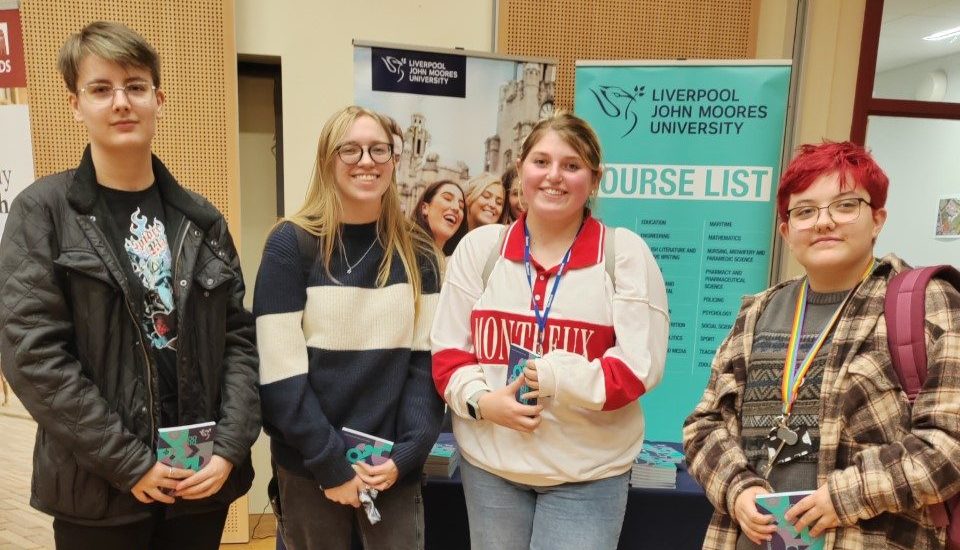 A group of four students stand together and smile at the camera