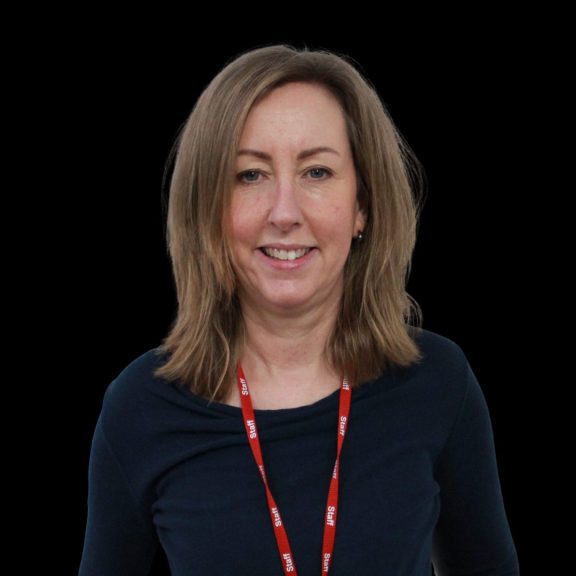 A woman smiles at the camera in front of a black background