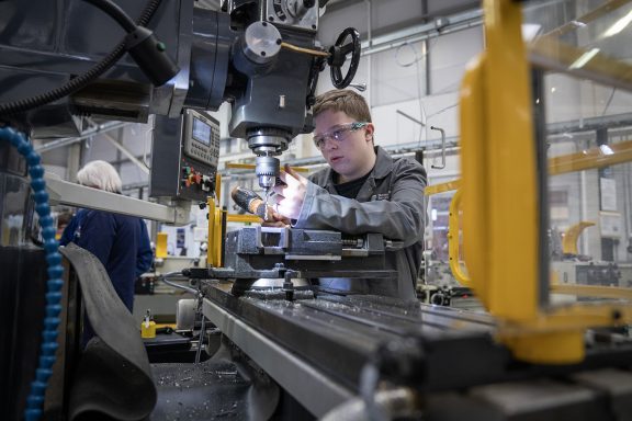 An apprentice working on a machine in an engineering workshop