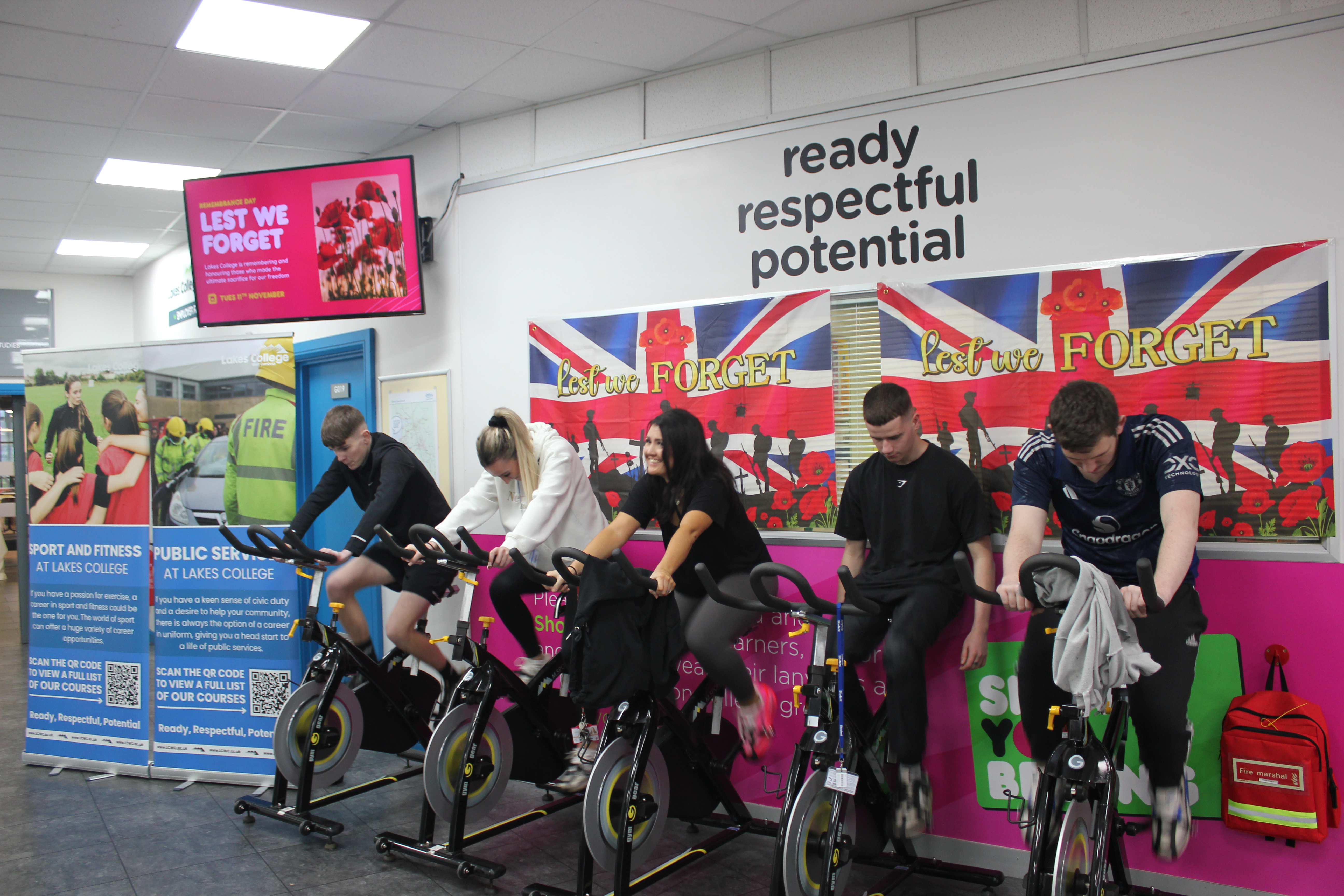 Four students and one staff member cycling on the spinning bikes in the Lakes College reception.